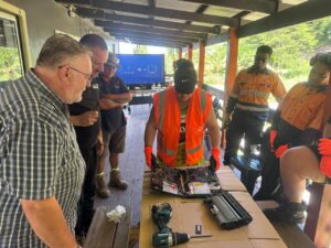 Trainer and participants dismantling a laptop during a practical e-waste training session.