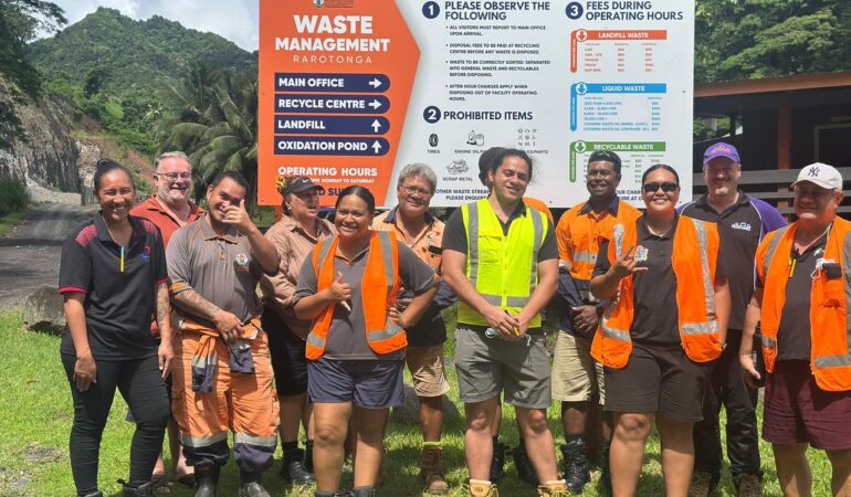 Group of waste management staff and trainers at Rarotonga standing in front of the Waste Management sign.